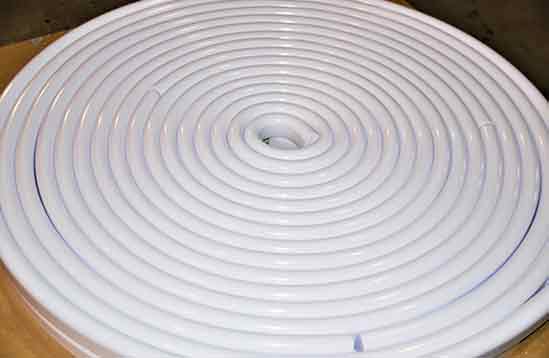 A white coil of plastic pipe sitting on top of a table.