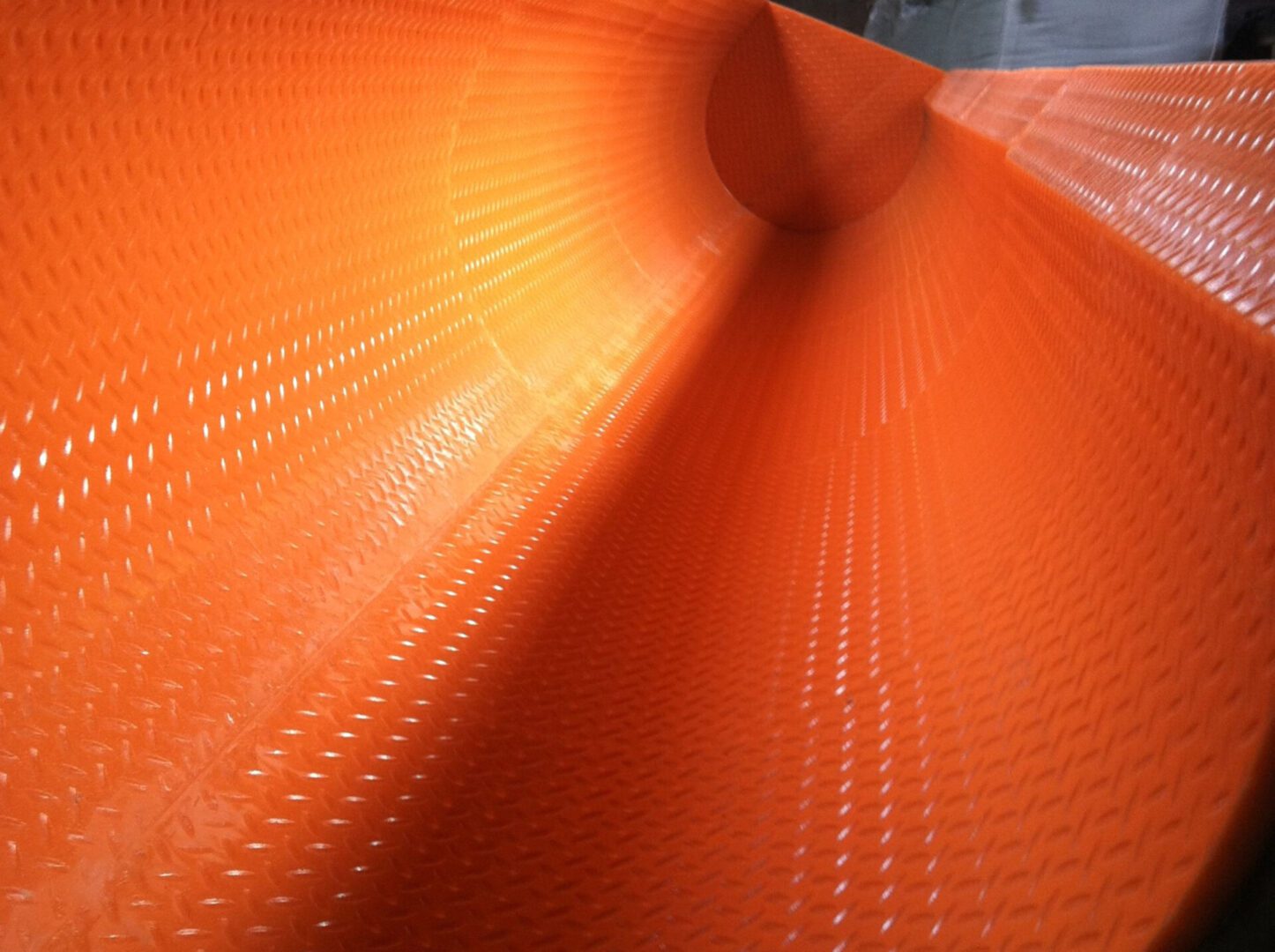 A close up of the orange surface of an industrial machine.