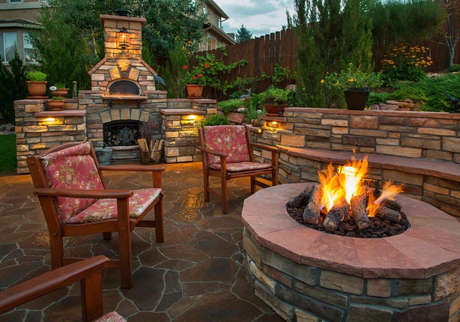 A fire pit with chairs around it and lights on.